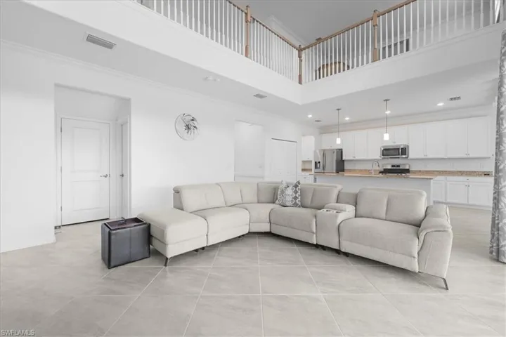 Living room with crown molding, a towering ceiling, light tile patterned floors, and recessed lighting