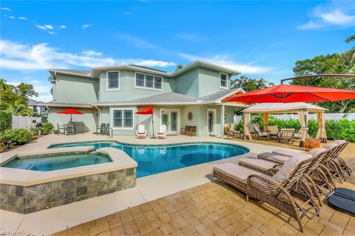 Back of house featuring a patio, stucco siding, a pool with connected hot tub, french doors, and outdoor dining area