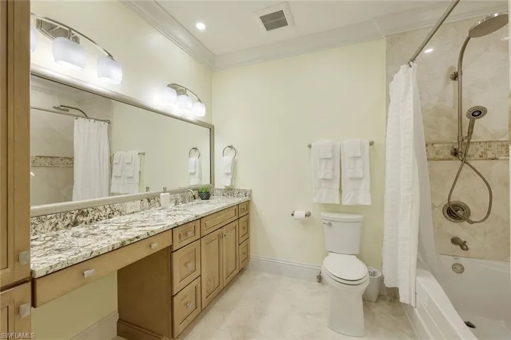Full bathroom with shower / bath combo with shower curtain, vanity, ornamental molding, and light tile patterned floors