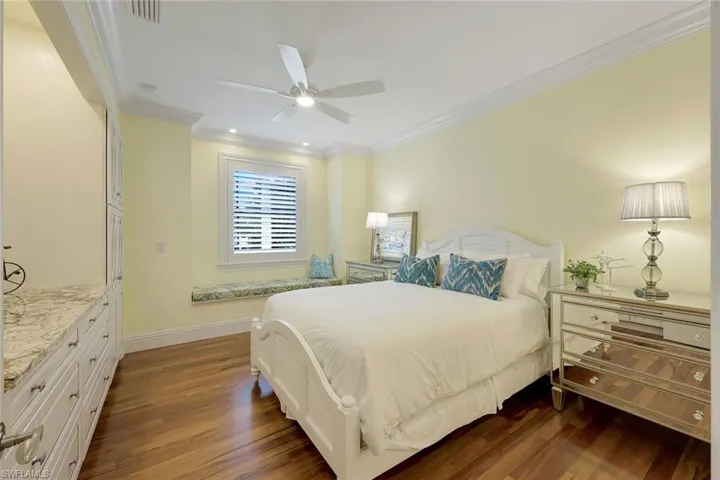 Bedroom with ornamental molding, dark wood finished floors, and a ceiling fan