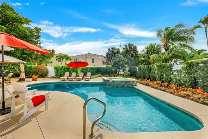 View of pool featuring a patio, a fenced backyard, and a pool with connected hot tub