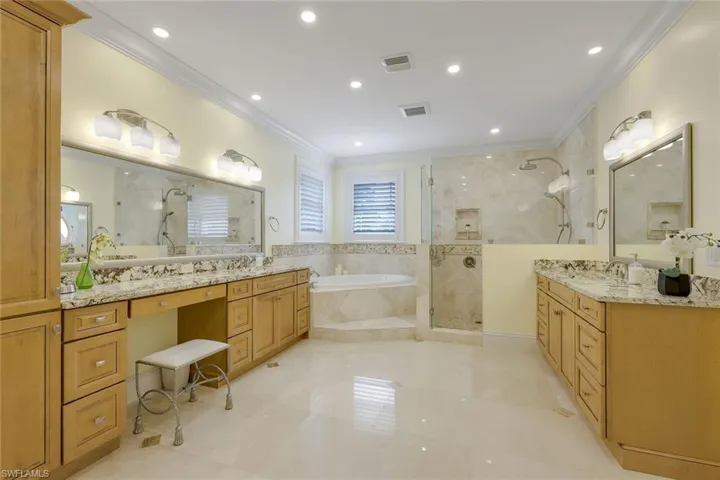 Full bathroom featuring a garden tub, ornamental molding, two vanities, a stall shower, and recessed lighting
