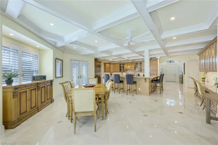 Dining area with coffered ceiling, beamed ceiling, arched walkways, recessed lighting, and french doors