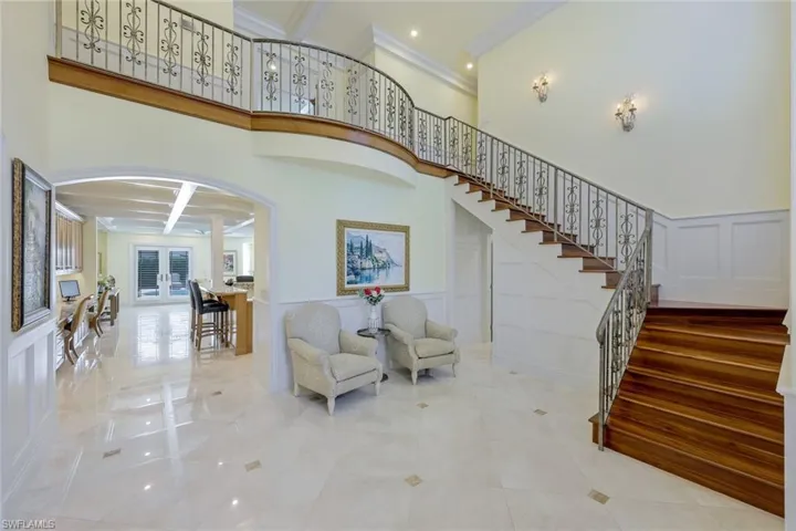 Stairs featuring arched walkways, a decorative wall, french doors, a wainscoted wall, and ornamental molding