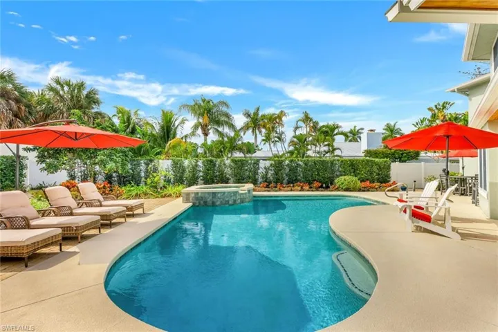 View of pool with a patio, a fenced backyard, and a pool with connected hot tub
