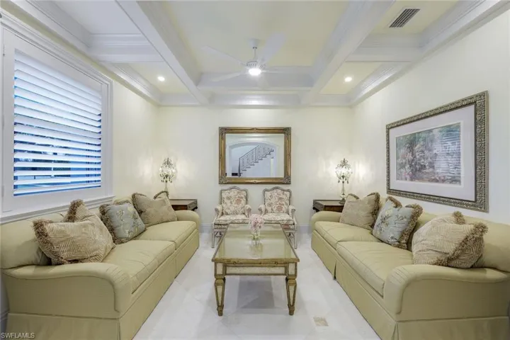 Tiled living room featuring beam ceiling, a ceiling fan, recessed lighting, coffered ceiling, and crown molding