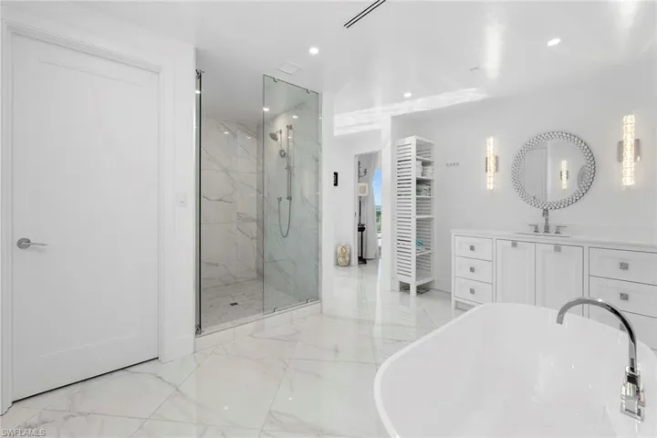 Full bath featuring vanity, a freestanding tub, a marble finish shower, recessed lighting, and light marble finish floors