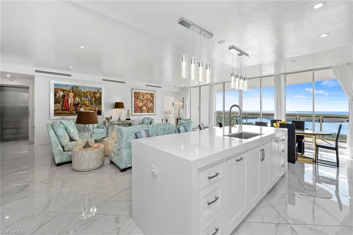 Kitchen with white cabinetry, pendant lighting, open floor plan, light stone countertops, and elevator