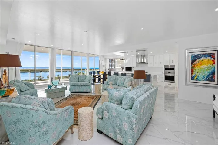 Living area with a water view, floor to ceiling windows, glossy white tile floors, and recessed lighting