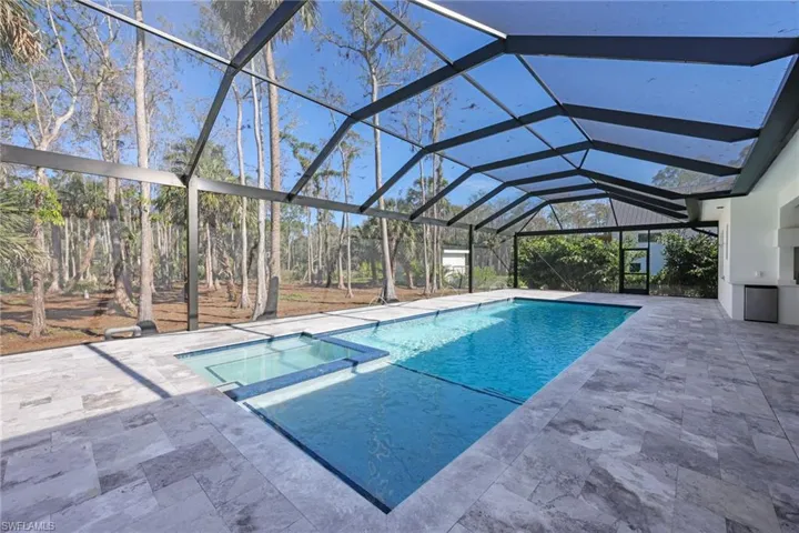 Oversized saltwater  gas heated pool with panoramic screen enclosure featuring deck jets and travertine deck, fireplace and custom ceilings