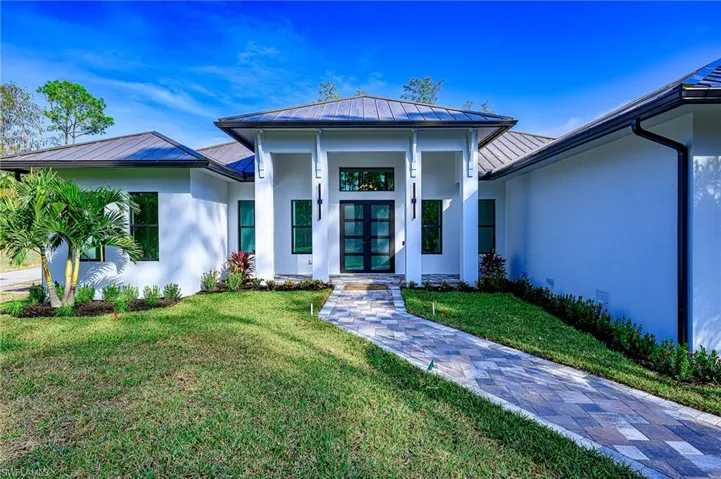 View of exterior entry featuring french doors and a yard