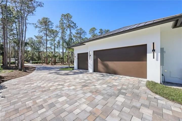 View of side of property featuring a 3 car garage with pull down stairs and epoxy floor