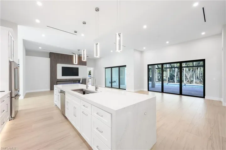 Kitchen with oversized island with dual faucets, waterfall quartz tops, wireless charging, custom built in wood, high end light fixtures and JennAir appliances with Butler pantry and additional refrigerator