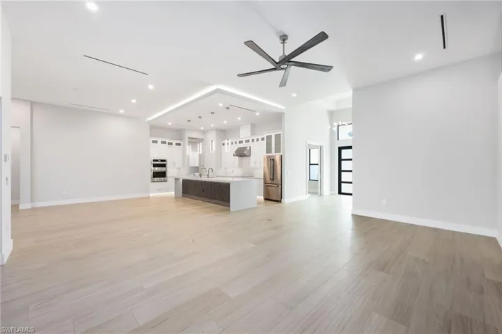 Unfurnished living room with ceiling fan with notable chandelier, light hardwood / wood-style floors, and sink