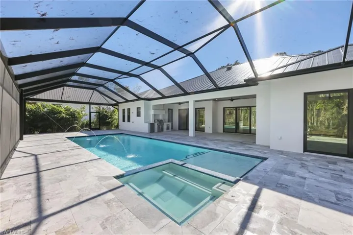 Oversized saltwater  gas heated pool with panoramic screen enclosure featuring deck jets and travertine deck, fireplace and custom ceilings