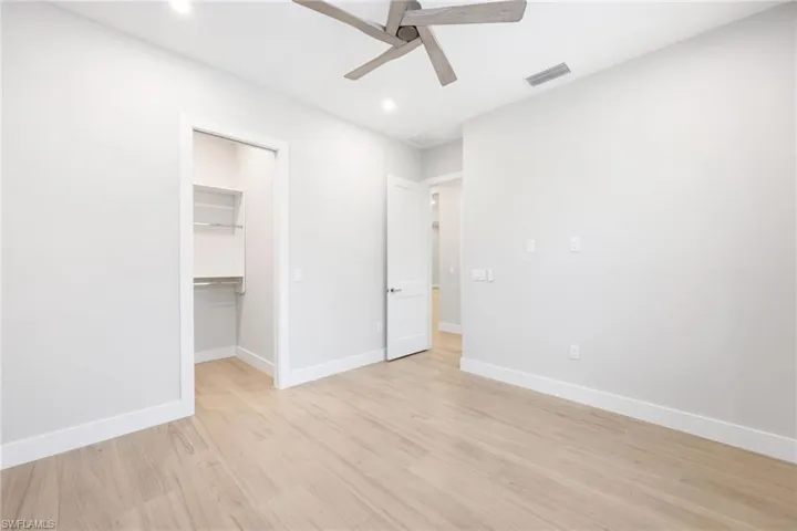 Unfurnished bedroom featuring a spacious closet with built-ins and ceiling fan
