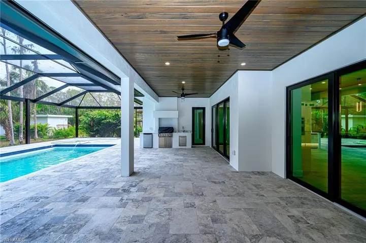 View of pool featuring a patio, grilling area, ceiling fan, and exterior kitchen