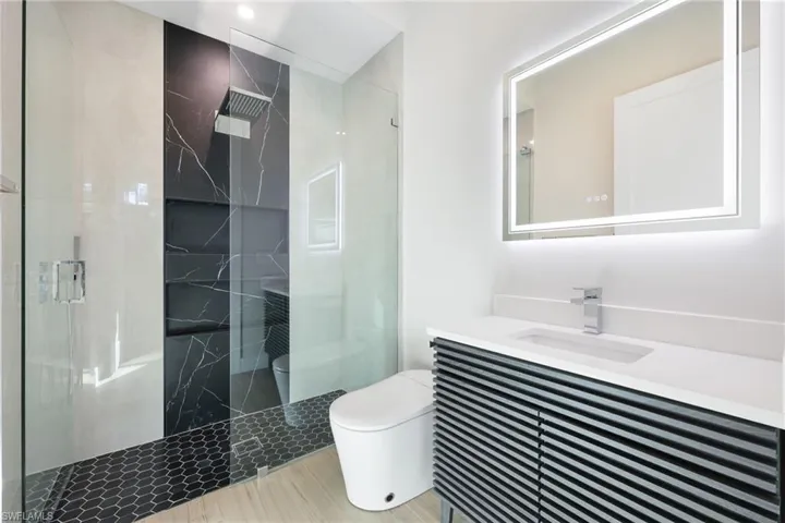 Bathroom featuring vanity, a shower with a glass shower door, and smart toilets throughout