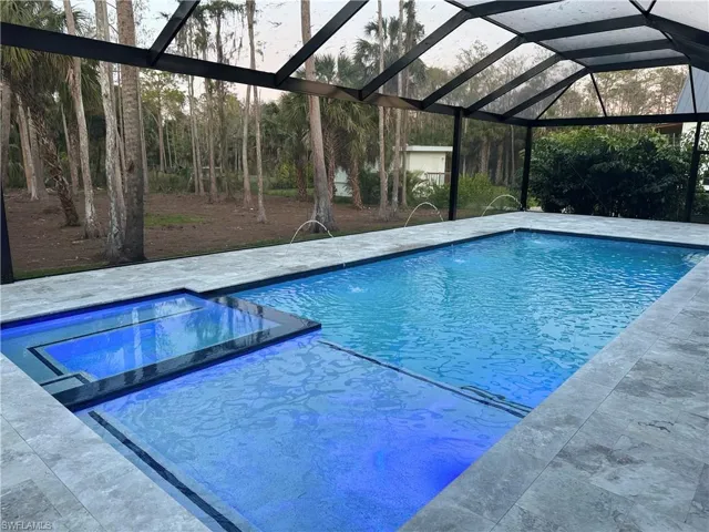 Oversized saltwater  gas heated pool with panoramic screen enclosure featuring deck jets and travertine deck, fireplace and custom ceilings