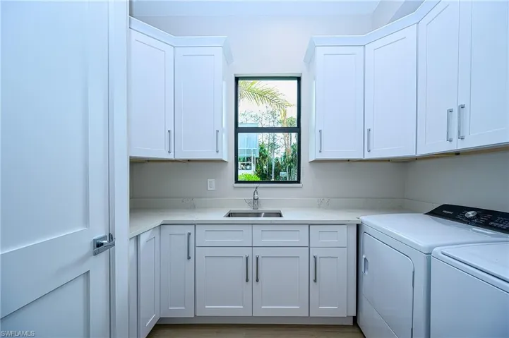 Laundry area with washer and clothes dryer, cabinets, and sink