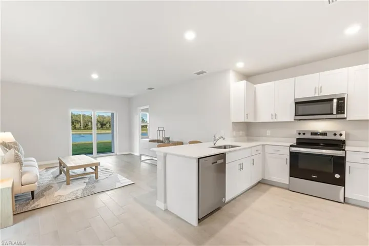 Kitchen featuring appliances with stainless steel finishes, open floor plan, a sink, light countertops, and a peninsula