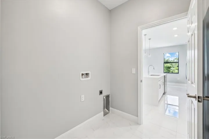 Clothes washing area featuring light tile patterned flooring, sink, hookup for an electric dryer, and hookup for a washing machine