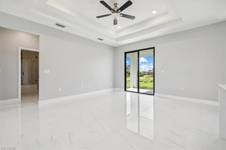 Spare room featuring light tile patterned flooring, ceiling fan, and a raised ceiling