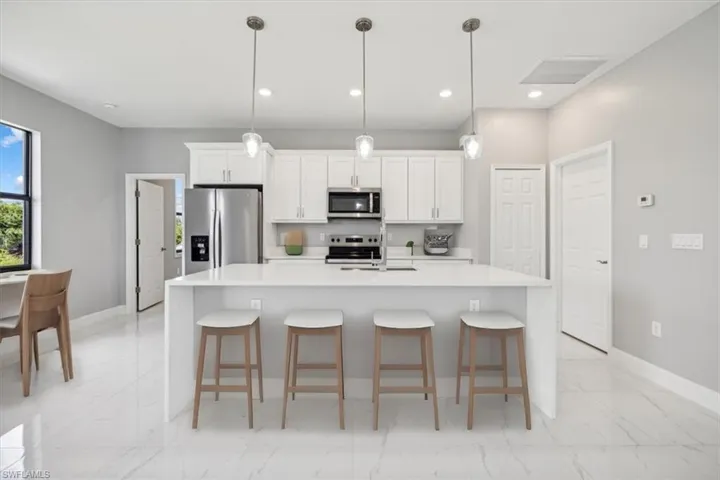 Kitchen featuring a kitchen island with sink, hanging light fixtures, stainless steel appliances, and light tile patterned floors