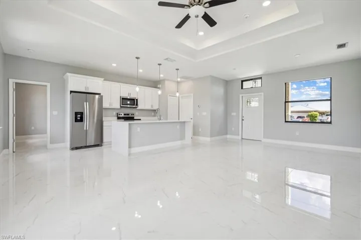 Kitchen with light tile patterned flooring, white cabinetry, pendant lighting, a kitchen island, and appliances with stainless steel finishes
