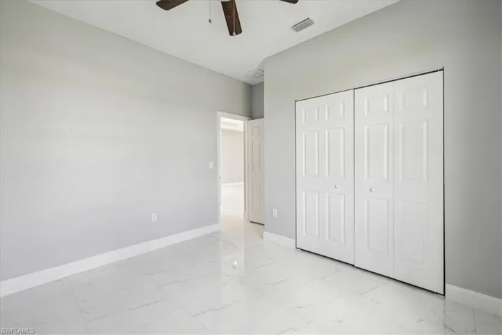 Unfurnished bedroom featuring light tile patterned flooring, ceiling fan, and a closet
