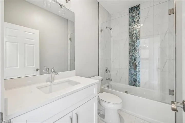 Full bathroom with tile patterned floors, toilet, vanity, and tiled shower / bath