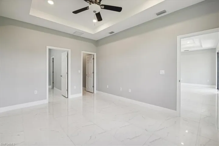Spare room with ceiling fan, a raised ceiling, and light tile patterned floors