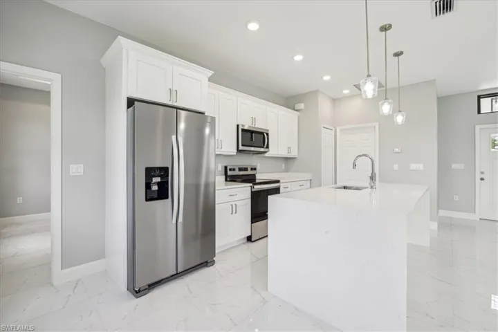 Kitchen featuring a kitchen island with sink, light tile patterned flooring, appliances with stainless steel finishes, and sink