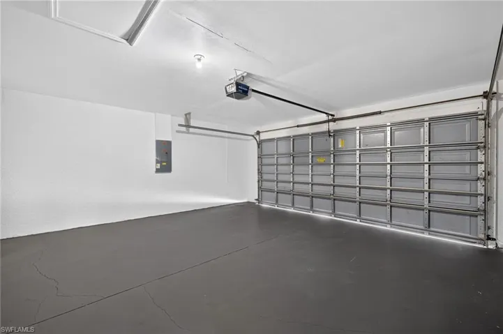 Spacious garage featuring a grey sectional garage door, painted concrete flooring, and ceiling-mounted lighting