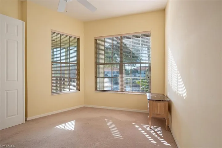 Carpeted spare room featuring plenty of natural light and ceiling fan