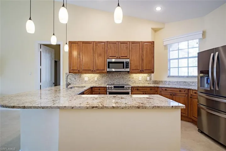 Kitchen featuring kitchen peninsula, sink, stainless steel appliances, and decorative light fixtures
