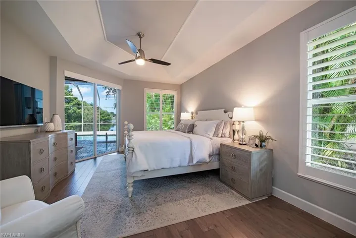 Bedroom with wood-type flooring, multiple windows, access to exterior, and ceiling fan