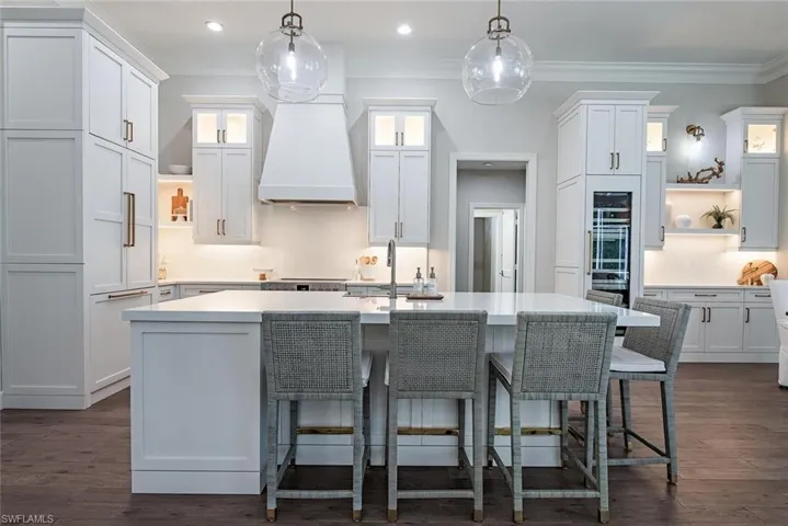 Kitchen with white cabinetry, dark hardwood / wood-style flooring, and a kitchen island with sink