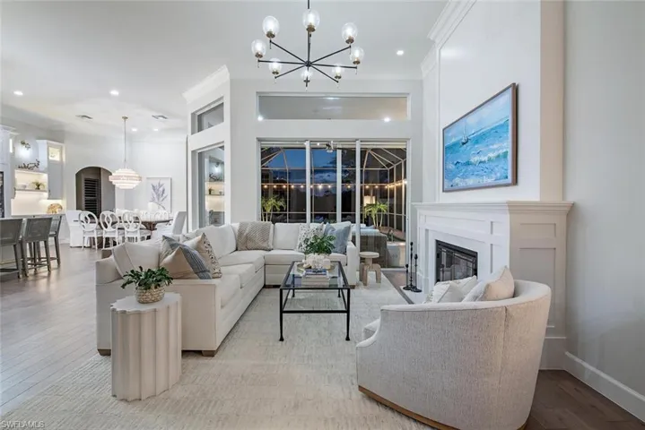 Living room featuring ornamental molding, an inviting chandelier, a fireplace, and light wood-type flooring