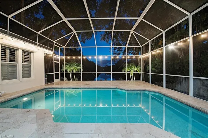 Pool at night featuring screen enclosure