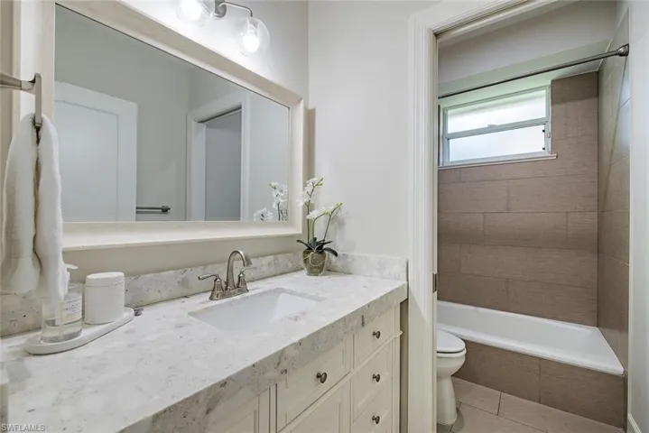 Full bathroom featuring tiled shower / bath combo, tile patterned floors, toilet, and vanity