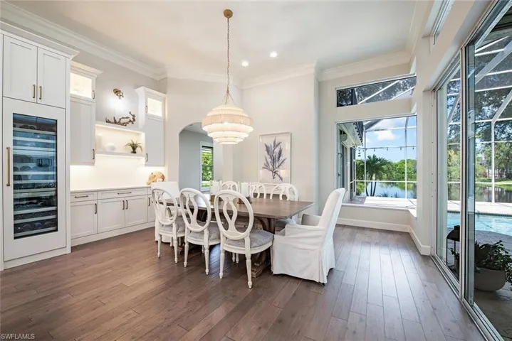 Dining area with ornamental molding, hardwood / wood-style flooring, and wine cooler