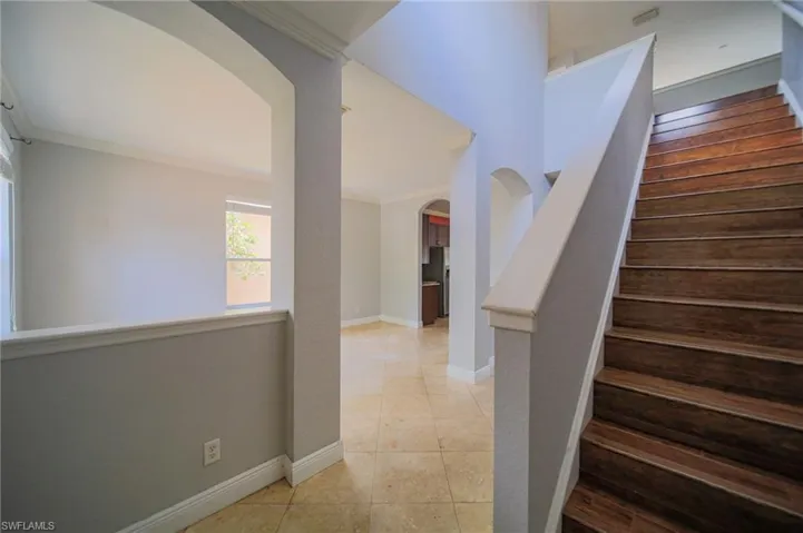 Stairs with tile flooring and crown molding