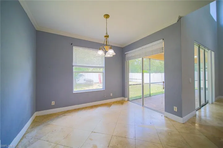Empty room featuring a chandelier, light tile flooring, and crown molding