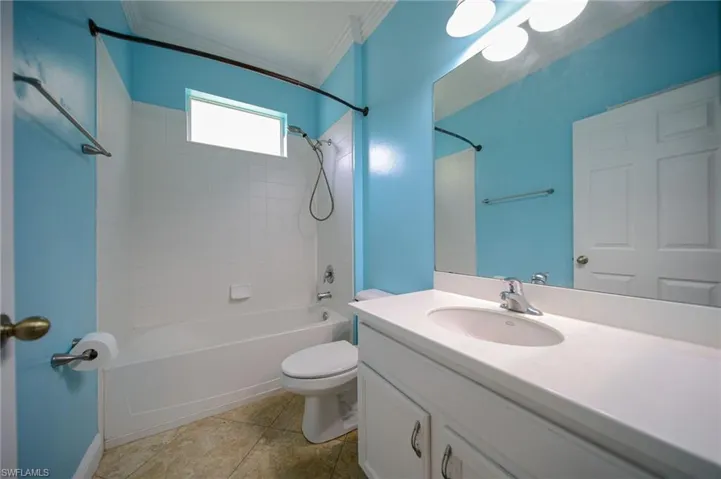 Full bathroom featuring crown molding, vanity with extensive cabinet space, tiled shower / bath, tile floors, and toilet