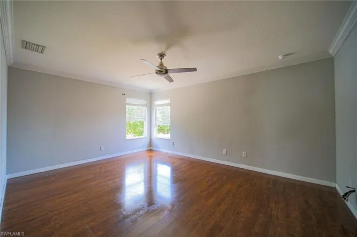 Spare room with ornamental molding, dark wood-type flooring, and ceiling fan