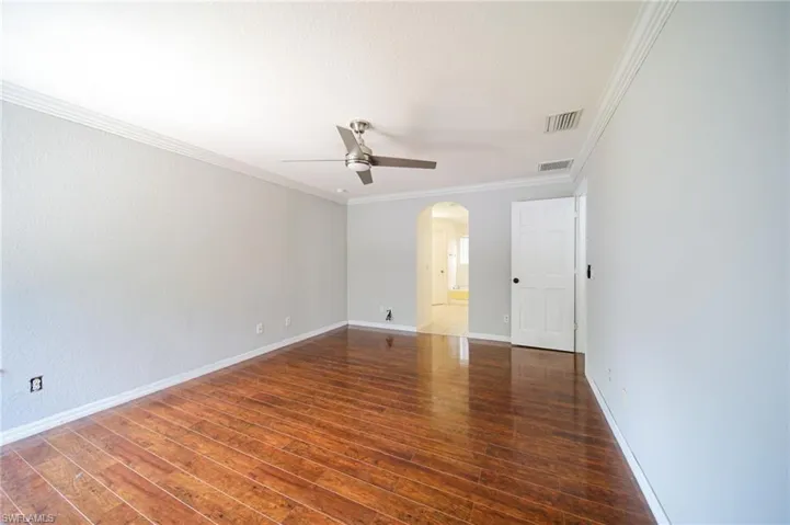 Empty room with ceiling fan, ornamental molding, and hardwood / wood-style flooring