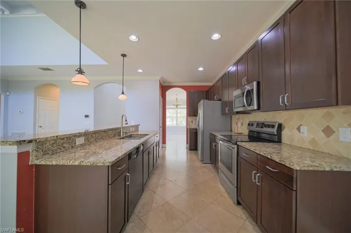 Kitchen featuring sink, pendant lighting, light stone countertops, and stainless steel appliances