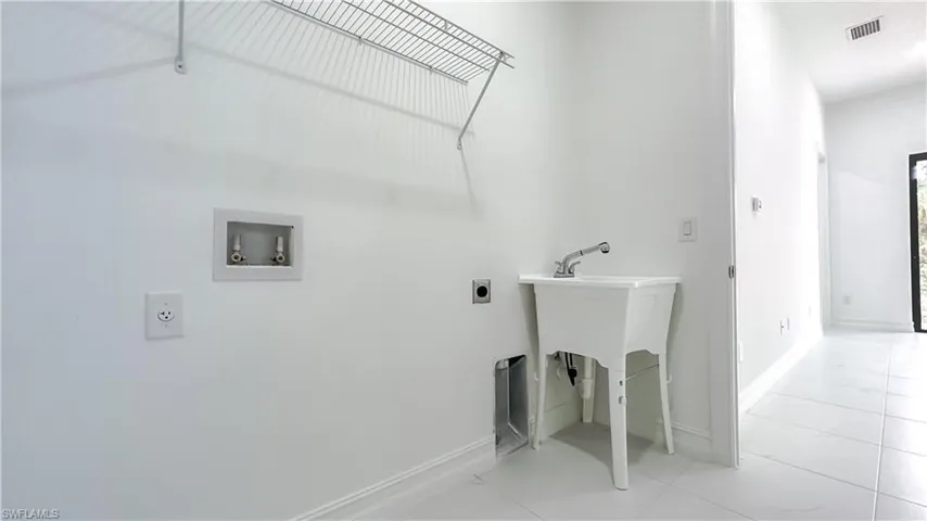 Laundry area with hookup for an electric dryer, washer hookup, and light tile patterned floors