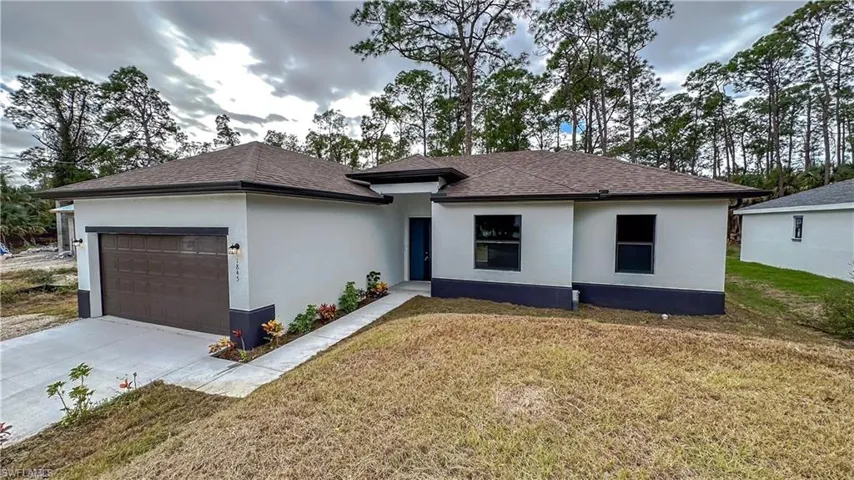 View of front of home with a garage, concrete driveway, a front lawn, stucco siding, and roof with shingles